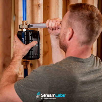 Technician performing professional installation of StreamLabs Water monitoring device for home water management system.